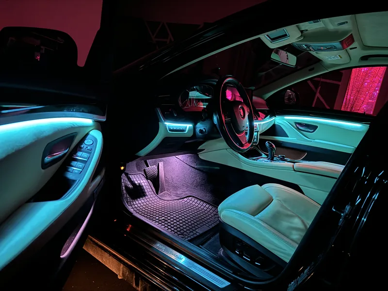 Blick durch die Fahrertür auf Cockpit und violetten Fußraum des BMW 3er F30