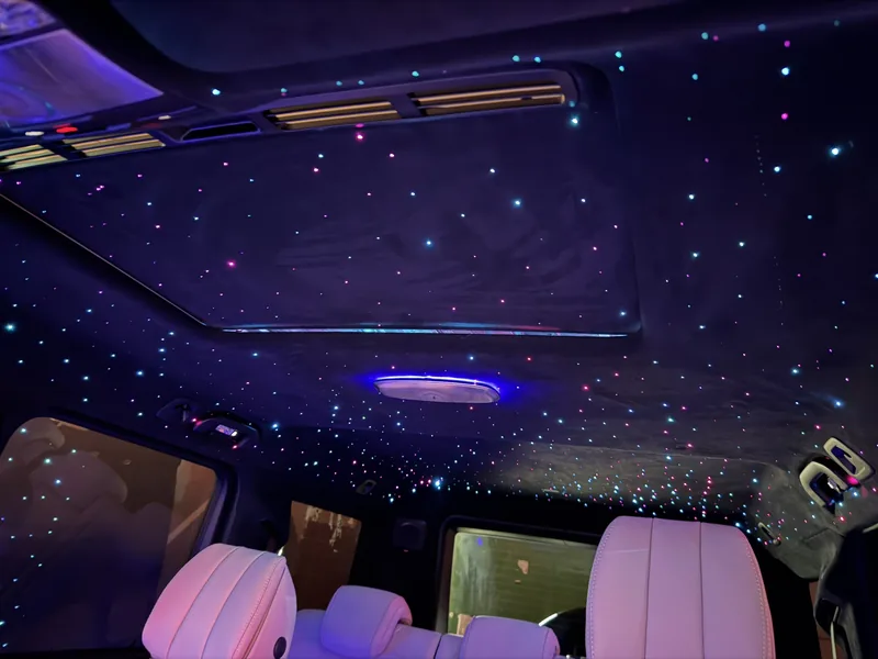 Sternenhimmel in der Mercedes G-Klasse mit hellen Sitzen und Lichtpunkten rund um die Dachbedienelemente